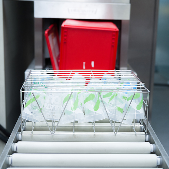 Stainless steel wash rack with reusable cups in front of the HOBART FUX cup washing system, high-performance solution for cleaning coffee-to-go cups at large events with low operating costs.
